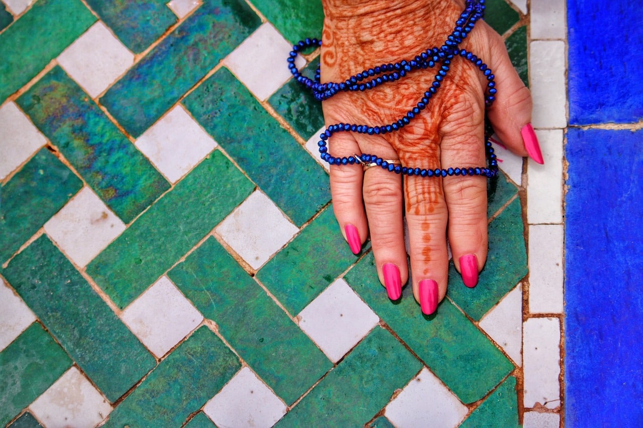 hand met henna en mala op gekleurde tegels