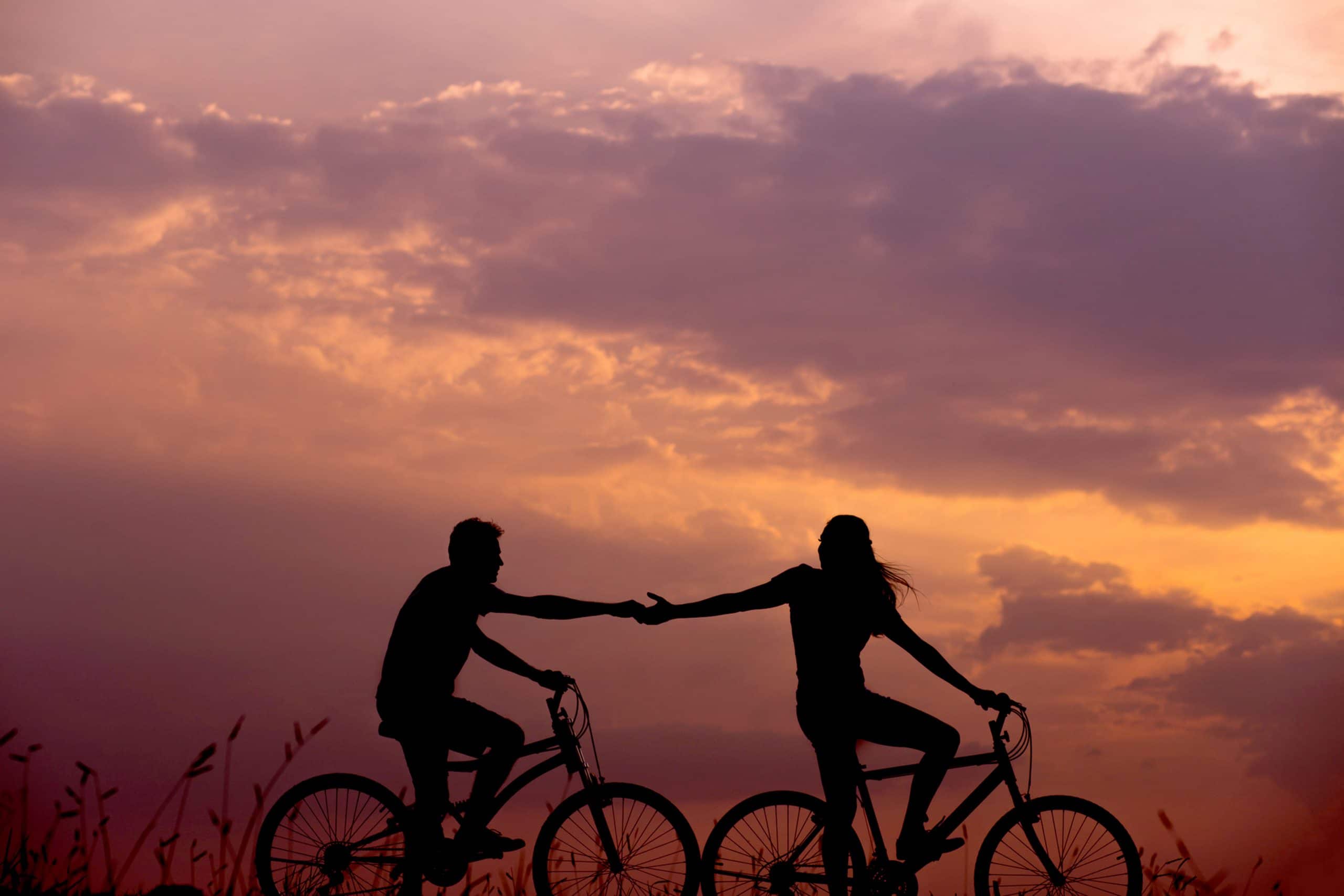 oranje roze lucht en fietsend koppel stel hand in hand