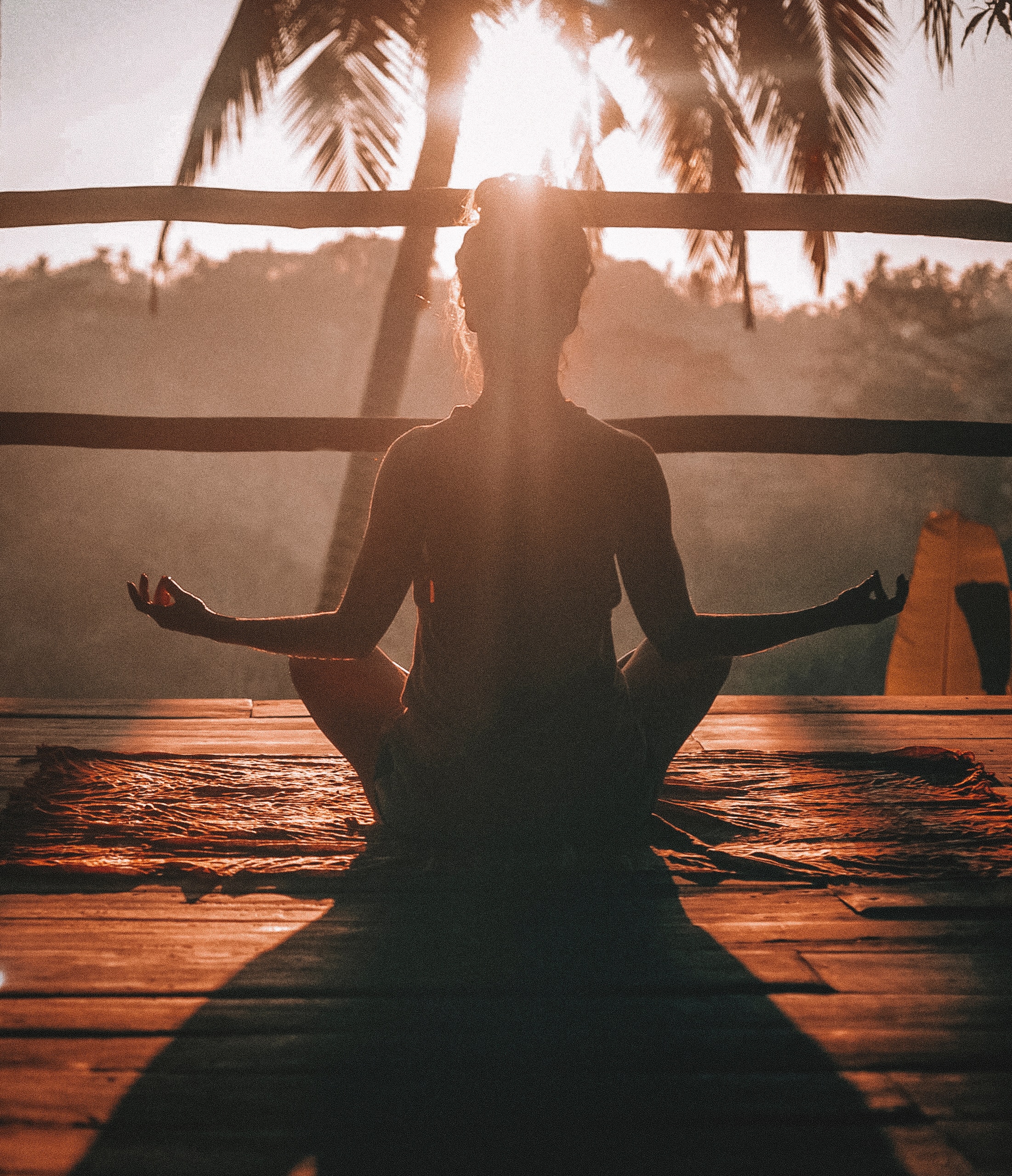vrouw in meditatiehouding in de zon yoga palmboom meditatie